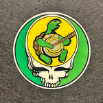 Circular sticker with a turtle, shell, and guitar on a green and yellow background