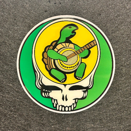 Circular sticker with a turtle, shell, and guitar on a green and yellow background