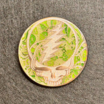 Circular object with a design of a skull and lightning bolt on a textured gray background