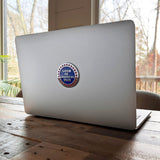 Laptop with a sticker on a wooden table by a window