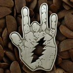 Metallic hand gesture pin on a textured brown background