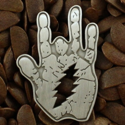 Metallic hand gesture pin on a textured brown background