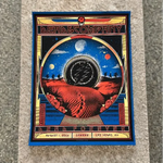 Concert poster featuring a cosmic desert landscape with planets and a central circular design in an art deco-style frame.