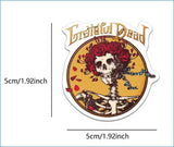 A circular, die-cut sticker featuring the grateful dead logo with a skull adorned in red roses and blue ribbons against an orange background.