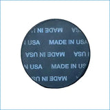 A round black coaster with 'MADE IN USA' printed in light blue, placed on a brown corrugated cardboard background.