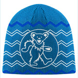 Blue knitted beanie featuring a white outlined grateful dead bear design on a circular background, accented with zigzag patterns in lighter blue and white.