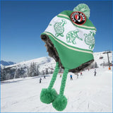 Green and white knit beanie with faux fur trim, embroidered turtle pattern, and a pom-pom on top.