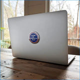 Laptop with a sticker on a wooden table by a window
