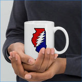 Person holding a white mug with a colorful design on a plain background