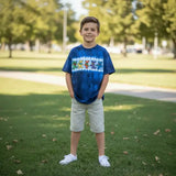 Child wearing a blue tie-dye shirt with colorful graphics standing on grass.