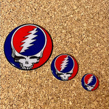 Set of three circular enamel pins featuring the iconic grateful dead skull and lightning bolt design in red, blue, and white.