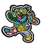 Colorful embroidered patch of a bear with floral and sun designs on a brown background