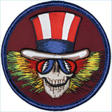 A circular embroidered patch featuring a skull wearing an american flag top hat and red, white, and blue sunglasses with lightning bolt designs.