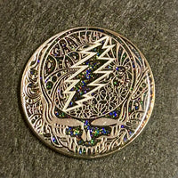 Metallic Grateful Dead ’Steal Your Face’ logo pin with ornate floral patterns and colorful crystal accents.