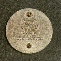 Circular metal plate with engraved text and two mounting holes.