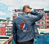 Denim jacket featuring a prominent red and blue grateful dead logo patch on the back.