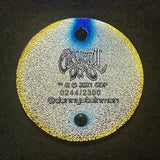 Metallic circular tag or medallion with engraved text and holographic edges.