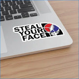 A black and white sticker with the text ’steal your face’ featuring a red, blue, and white grateful dead skull logo.