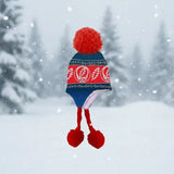 Red and blue knitted hat with pom-poms on a snowy background