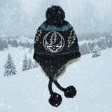 Black knit hat with pom-poms and a skull design against a snowy background