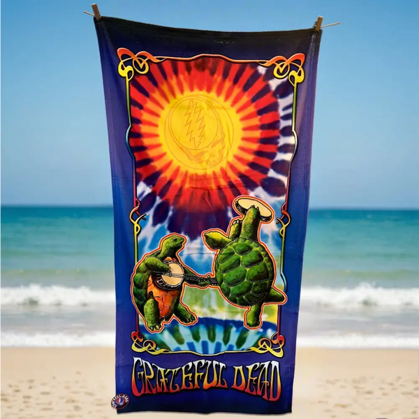 Beach towel featuring dancing turtles and a vibrant sun design with ’Grateful Dead’ text.