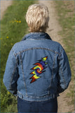 Blue denim jacket featuring a vibrant, multicolored embroidered lightning bolt design on the back.