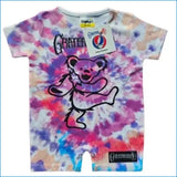 A baby short-sleeve romper featuring a Grateful Dead Grateful Bear graphic on a purple, pink, and blue tie-dye patterned background. The romper has a white inner collar, snap closures at the crotch, and a 'Grateful Dead' brand patch on the lower hem.