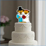 A colorful cartoon bear wedding cake topper featuring a groom in blue and white attire with a black top hat, and a bride in a white dress holding red roses.