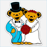 A vibrant, cartoon-style sticker featuring two smiling grateful dead bears dressed in wedding attire — one in a blue tuxedo with a black top hat and bow tie, the other in a white gown adorned with red roses on her head — holding a