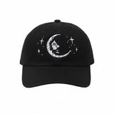 Black baseball cap featuring a white embroidered crescent moon with a face and surrounding stars.